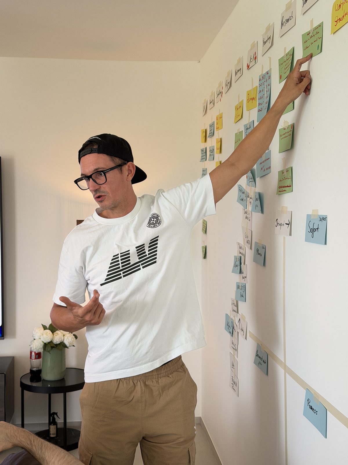 Alexander Ferati vor einer Wand mit Prozesskarten